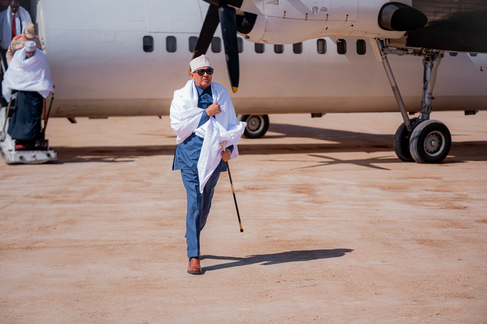 Madaxweynaha Somaliland Cabdiraxmaan Cirro oo kasoo degaya diyaaraddii uu ku tagay magaalada Ceerigaabo, isagoo xidhan koofiyad dhaqameed, gashan maryo caddaan ah, gacantana ku haya ul socod.